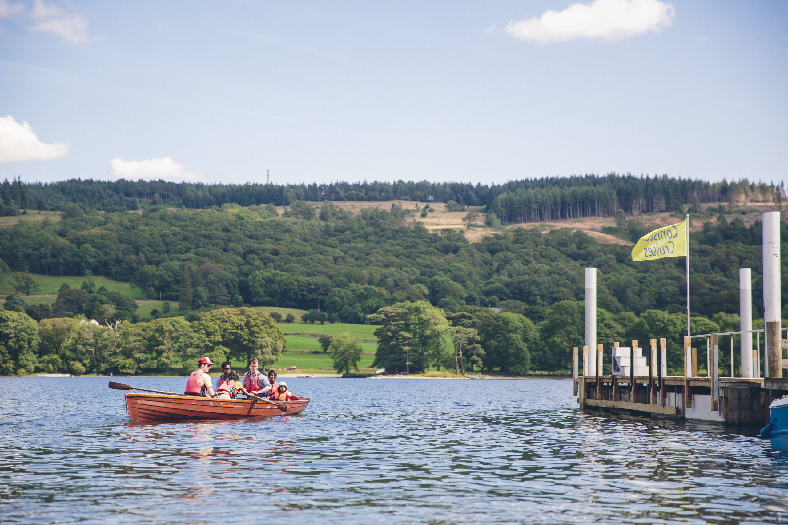 family in a wooden rowing boat on coniston water on a sunny day