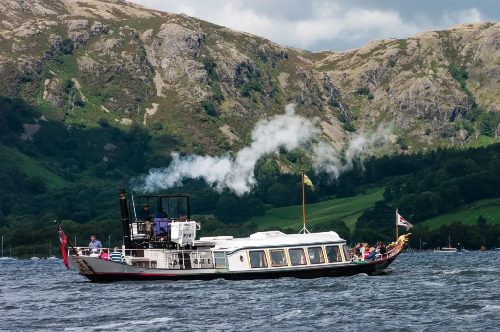steam yacht gondola on coniston water with rocky fells and green woodland in the back drop